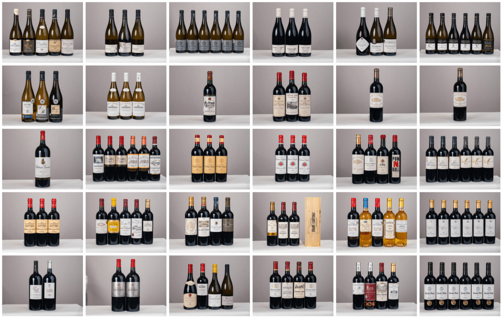 le forum du rotary une grille de trente cinq étagères présente des groupes de bouteilles de vin, la plupart par paires ou par trios, avec des étiquettes et des formes variées, disposées proprement sur un fond gris clair uni, comme une collection de vente organisée.