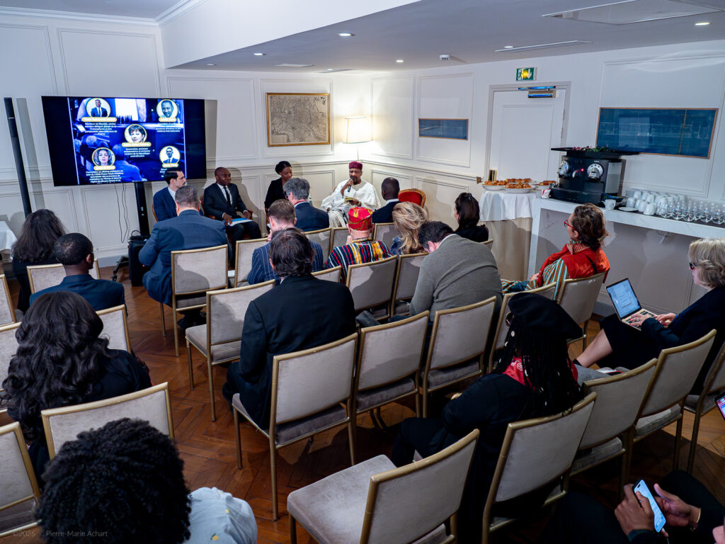 le forum du rotary un groupe de personnes est assis dans une salle de conférence face à un panel d'orateurs et à un grand écran affichant des informations ; certains participants prennent des notes ou utilisent des ordinateurs portables. certains participants prennent des notes ou utilisent des ordinateurs portables. au fond de la salle se trouve un espace de rafraîchissement avec des tasses et des en cas.